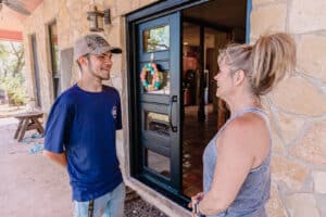 tech speaking with a happy customer outside of her home